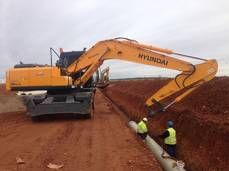 Excavadora realizando la colocación de tubos para la canalización.