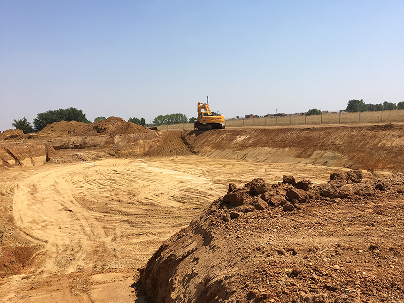Excavadora realizando trabajos de saneamiento y obra civil en terrenos.