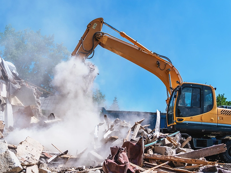 Excavadora con martillo hidráulico realizando la demolición y derribo de una casa.